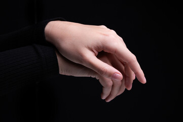 Female hands on a black background. Concept of tenderness and self-care.