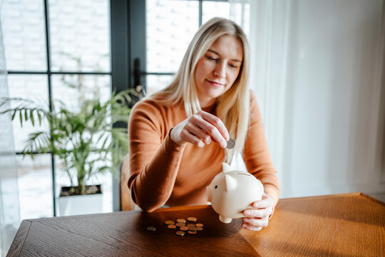 Woman saving money in a piggy bank at home