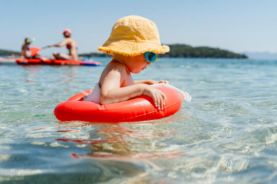 Child learning to swim with a float during a summer vacation at the sea