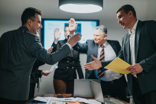 A group of business professionals in a modern setting engaging in teamwork and celebration, reflecting success and collaboration.