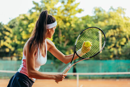 Female tennis player with racket and ball playing at sports court