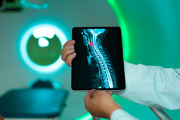 Doctor holding a tablet displaying a spine MRI in a medical setting