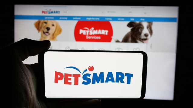 Stuttgart, Germany - 05-25-2025: Person holding cellphone with logo of US pet retail company PetSmart Inc. on screen in front of webpage. Focus on phone display.