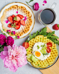 Belgian waffles with sweet and savory filling, strawberries, cream cheese, herbs, vegetables, egg. Breakfast waffles with coffee. Top view