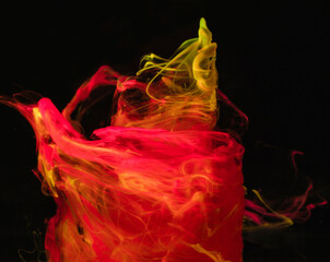 Vibrant ink tornado shapes swirling in water against a black background