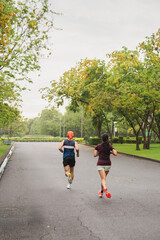 Unidentified couple training jogging in the park outdoors in summer.