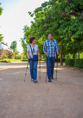 Senior couple walking in park with hiking poles