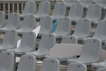 Fototapeta premium The vibrant photo showcases a neat arrangement of modern gray plastic seats at a colorful outdoor venue, accented by bright paper, creating a cheerful atmosphere for passersby