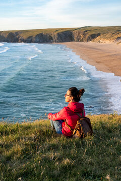 Woman with backpack looking away while sitting on grass