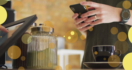 Image of falling yellow dots over people using payment terminal
