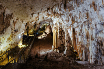 Stalactites and stalagmites creating stunning formations in illuminated cave
