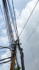 Network of internet provider cables on electric poles, with a cloudy blue sky