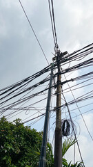 Network of internet provider cables on electric poles, with a cloudy blue sky