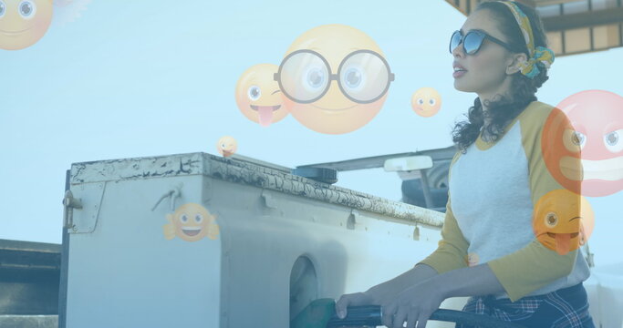 Image of emoji icons over woman fueling car - Powered by Adobe