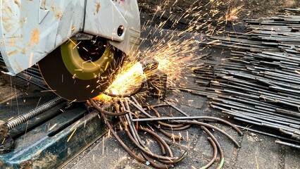 Close-up of a construction worker cutting iron rods with an electric cutting machine