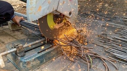 Close-up of a construction worker cutting iron rods with an electric cutting machine