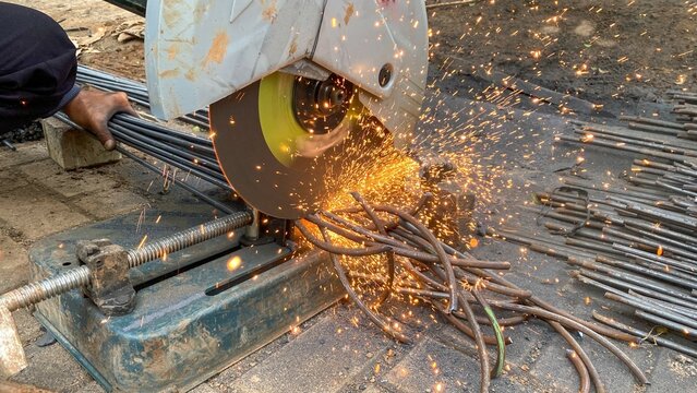 Close-up of a construction worker cutting iron rods with an electric cutting machine - Powered by Adobe