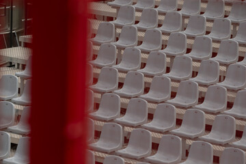 In an auditorium setting, you can see rows of empty white plastic chairs that are neatly arranged,...