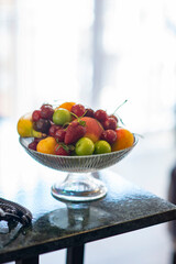 Colorful fresh fruit bowl on hotel room counter with armchair and bed showing in the background