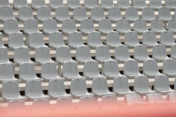 Naklejka premium The image shows a wideangle view of neatly arranged grey plastic seats in a stadium, highlighting an empty section without spectators, emphasizing the venues overall emptiness