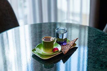 Turkish coffee with chocolate and water on a marble tabletop in a hotel room setting with soft window light