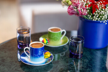 A welcome gesture at a hotel, Turkish coffee for two with chocolate and water on a marble tabletop in a hotel room setting with soft window light