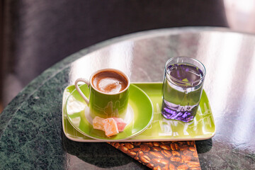 A welcome gesture at a hotel, Turkish coffee with Turkish delight sweets and water on a marble tabletop in a hotel room setting with soft window light