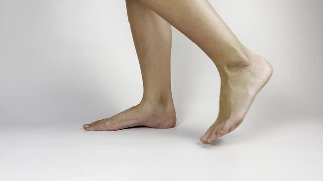 Side view close-up of woman’s legs: left leg steps back, right remains still. Demonstrates controlled movement, stability, and coordination. Ideal for fitness or motion study visuals
