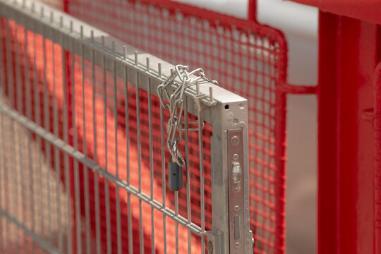 Closeup of a metal gate secured with a chain and padlock, showcasing a barrier in a fenced area