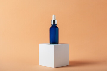 Blue glass cosmetic bottle, Skin care or sunscreen cosmetic with stylish props on cream background.