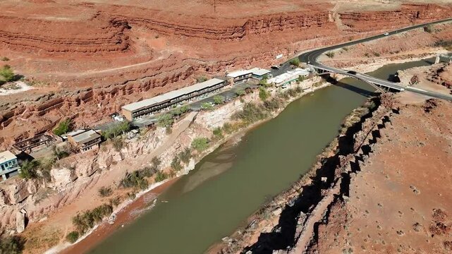 Aerial View of Mexican Hat Utah, Hotels and parking lot with views of San Juan River and Jason R. Workman Memorial Bridge, push in shot, Brush and Vibrant Orange Cliffs, Highway 163
