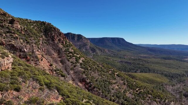 Close up View of Mountains, Aerial view, push in shot, Mogollon Rim in Payson Arizona, covered in trees, early summer, blue skies and jagged edges