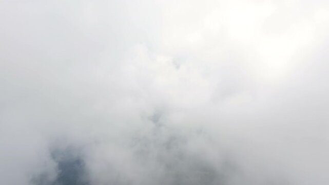 Drone flying through the clouds to reveal a dense jungle beneath.