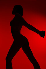 silhouette of a woman sport fitness stretching her arms and legs with a red background, emphasizing strength, health and active lifestyle in dynamic motion