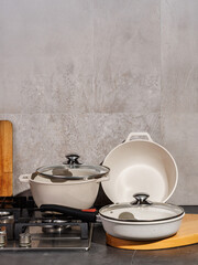 A set of white pots and pans are neatly placed on a stove top