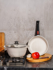 A pot and pan are on a stove by a cutting board with veggies