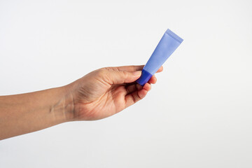 Purple packaging for cream, sunscreen or serum in hand on white background.