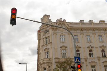 A bright red traffic light stands prominently in front of an impressive historical building,...