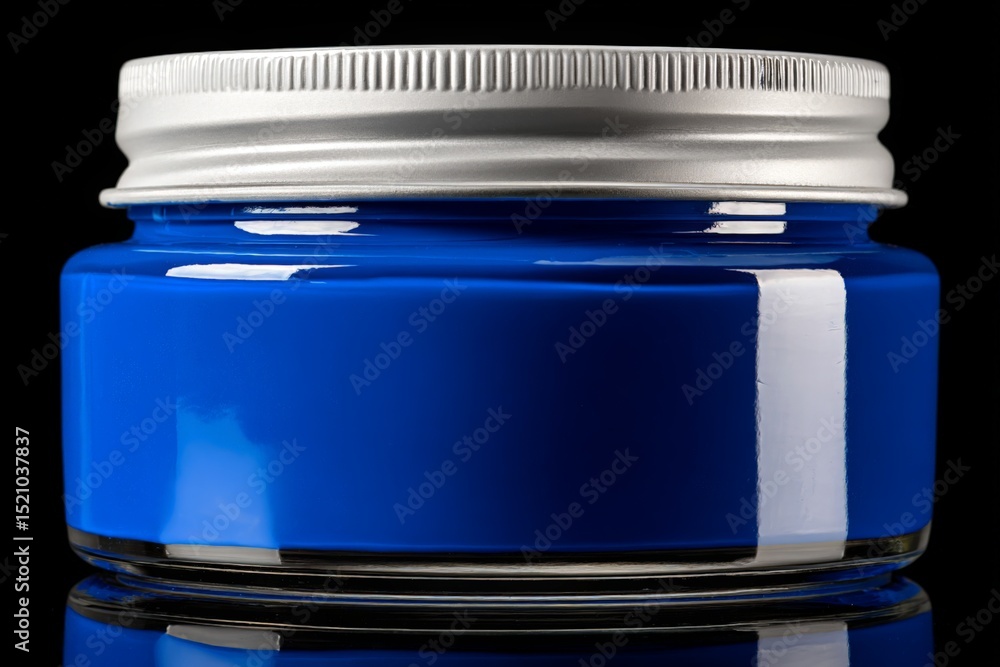 Poster bright blue paint in a clear glass jar with a metallic lid on a black background capturing various s