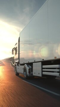 A long distance semi truck with cargo trailer passes the camera driving on a desert road into the sunset. Low angle camera. 3d animation rendering. Vertical Video