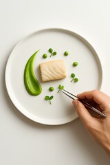 Artistic food styling with tweezers on white plate, top view food styling with microgreens and puree in minimalist setup, Elegant dish with fresh green elements and protein.