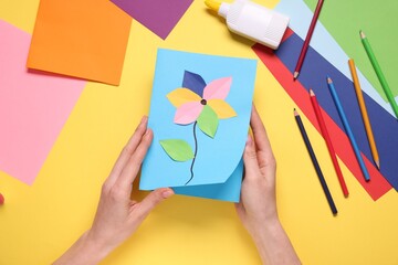 Woman with postcard on yellow background, top view. Child handmade craft