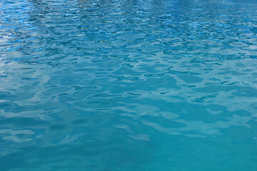 Gentle Ocean Ripples on a Clear Day. A close-up view of gentle ripples on a tranquil turquoise sea, capturing the calm and serenity of the ocean surface under natural daylight.