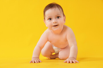 Cute little baby crawling on yellow background