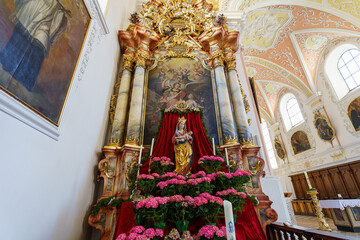 Catholic altar adorned with flowers and a statue in a historic church during daylight