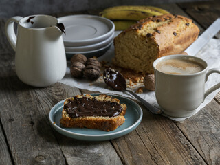 Artisanal and slow breakfast on a wooden table with natural side light. Banana bread with...