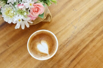 Coffee latte art milk foam on cup and artificial flowers