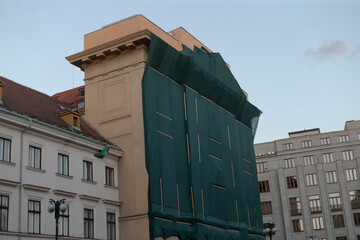 A large building facade is covered in vibrant green netting, signaling renovations in the busy...