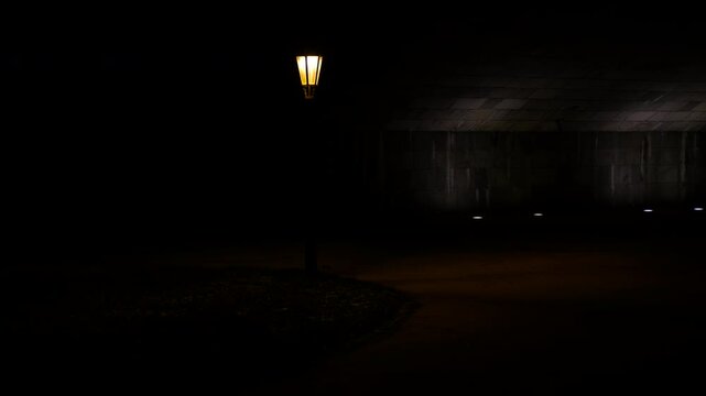 Retro lantern under the bridge. Light decreasing under a bridge at night. Darkness gradually consuming street lamp beneath urban bridge, casting deep shadows