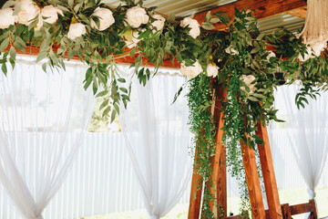 White table with a green plant on it. The table is in front of a white curtain